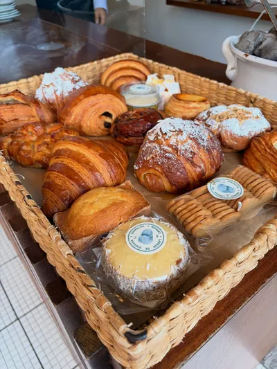 A basket of croissants, pain au chocolat, and other pastries at a bakery counter